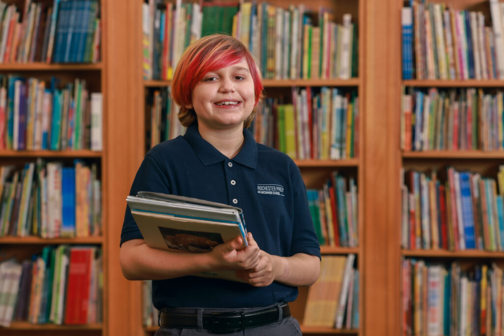 student in front of shelves of books holding books