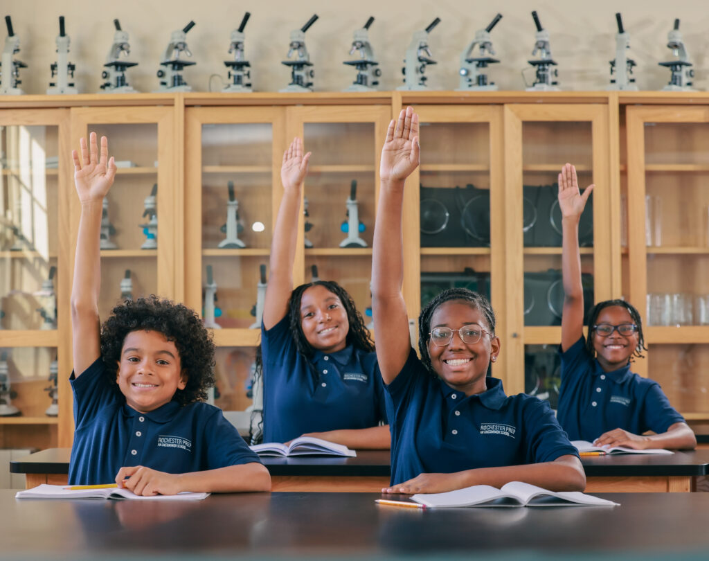 Students sitting in science lab raising hands 